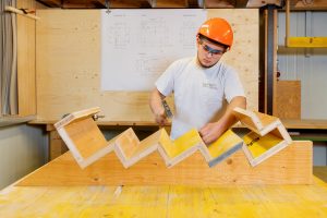 Typische Arbeitssituationen von Betonwerkern: Auszubildender fertigt Holzverschalung an.